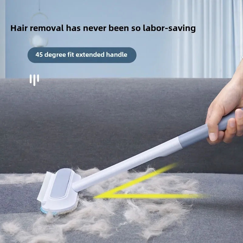A hand is using a long-handled static pet hair remover brush to clean pet hair from a surface.