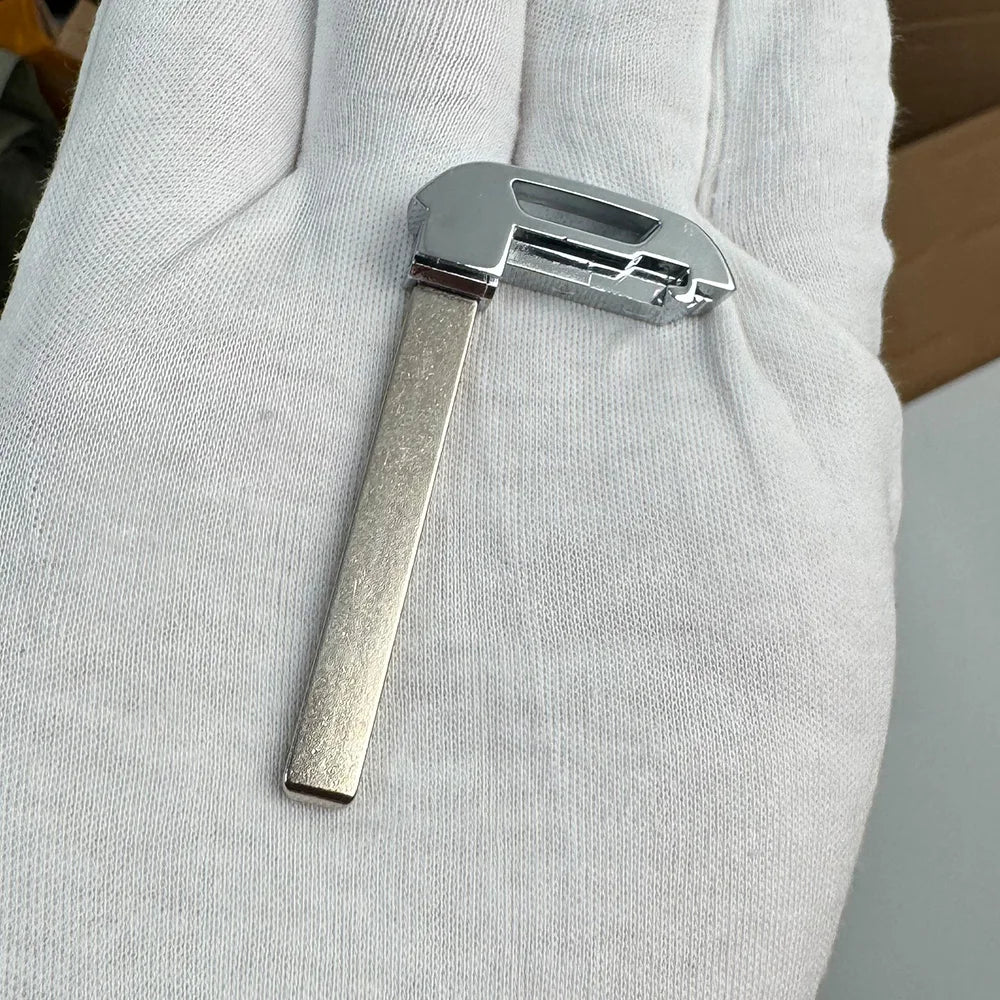 A close-up of a silver aftermarket remote key for Chevrolet trucks and SUVs held in a person's hand.