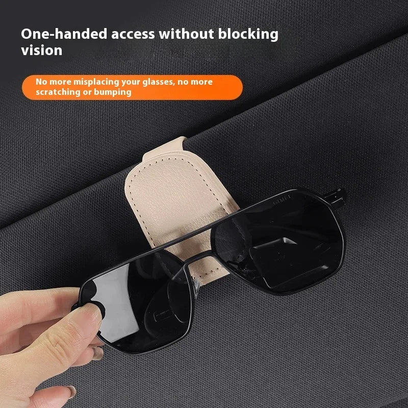 A hand is placing a pair of black sunglasses onto a light tan magnetic leather holder.
