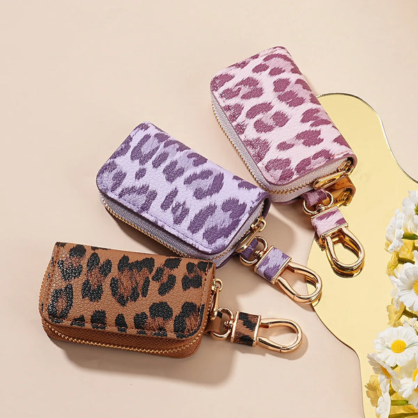 Una colección de llaveros para coches con estampado de leopardo morado y marrón, exhibidos sobre un fondo claro.