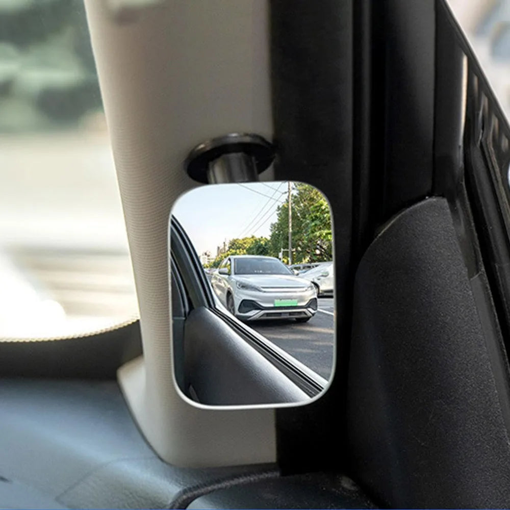 A close-up view of a 360° adjustable HD blind spot mirror mounted on a car door frame.