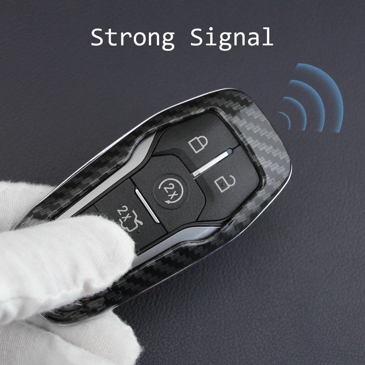 A hand holds a black carbon fiber style key fob cover with a metal chain, demonstrating a strong signal.
