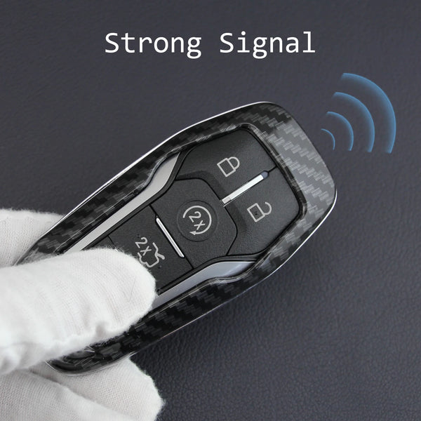 A hand holds a black carbon fiber style key fob cover with a metal chain, demonstrating a strong signal.