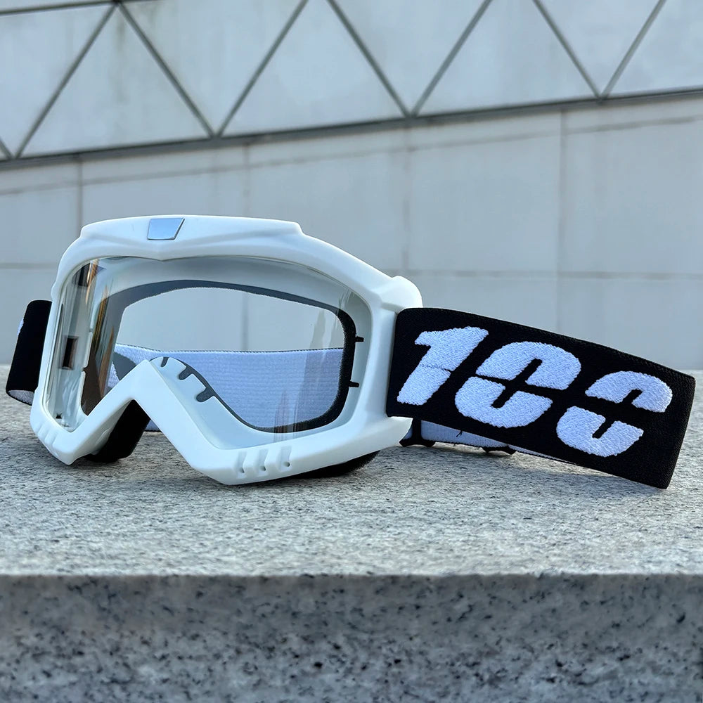 White windproof sports goggles with black strap resting on a gray stone surface.