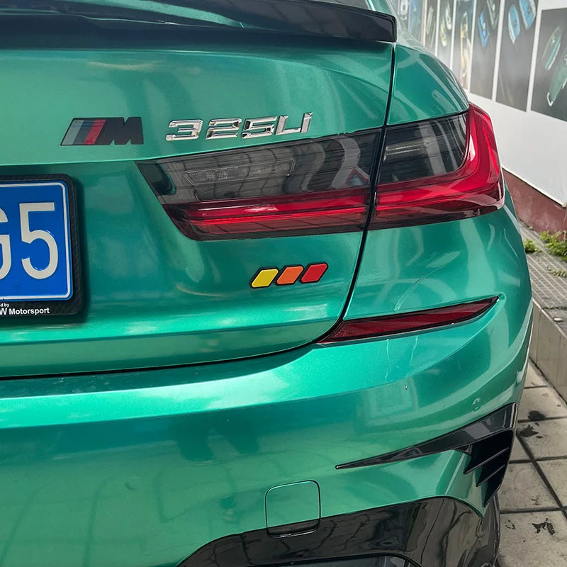 Rear view of a green BMW M3 325i with black trim and a blue license plate.