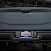 Close-up of a gray vehicle's rear bumper with a license plate frame displaying a Texas plate.
