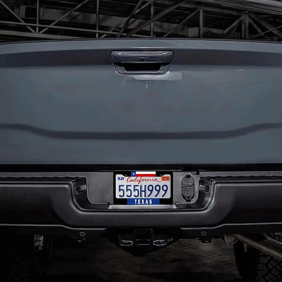 Close-up of a gray vehicle's rear bumper with a license plate frame displaying a Texas plate.