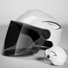 A white helmet with a clear visor is shown on a gray surface.