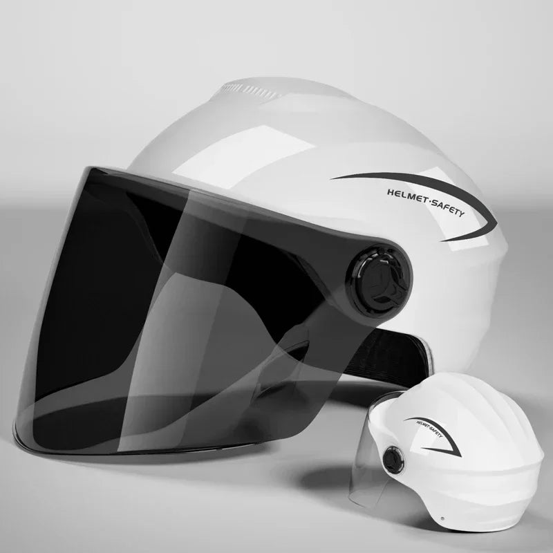 A white helmet with a clear visor is shown on a gray surface.