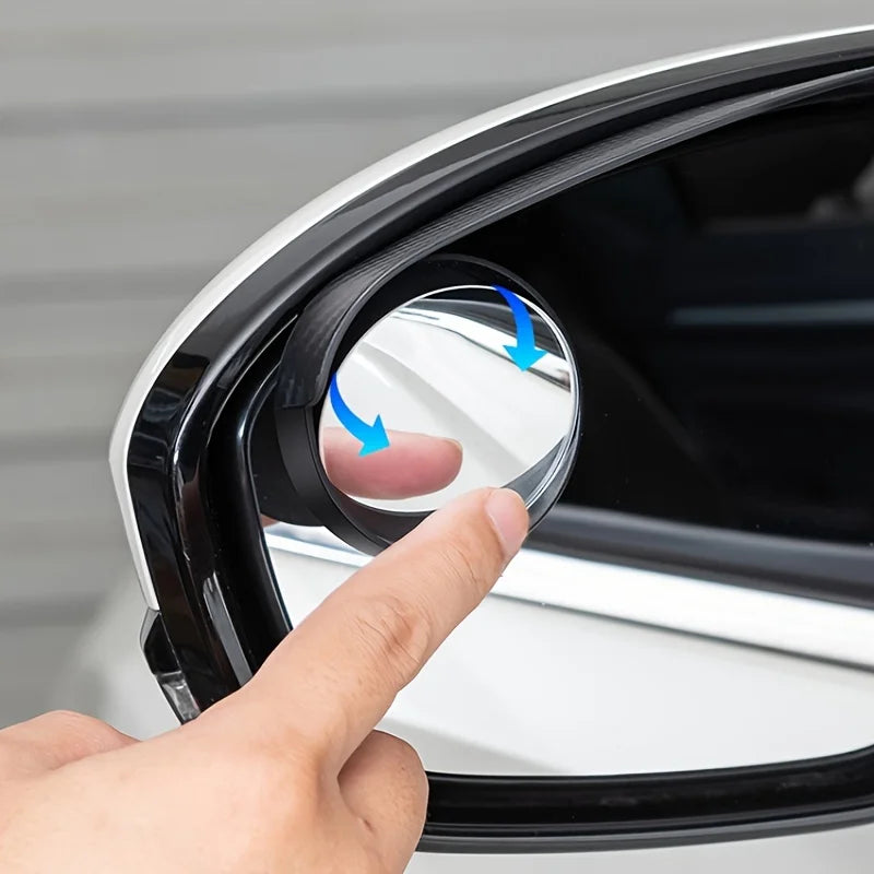 A hand is adjusting a dual car blind spot mirror with rain shield on a vehicle door.
