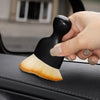 A hand holds a black and natural fiber curved silicone brush for cleaning car interiors.