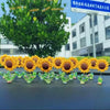 Une guirlande d'ornements de tournesols jaunes avec des tiges vertes sur une surface sombre.