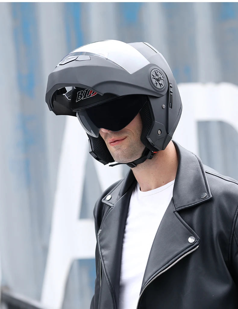 A man wearing a black motorcycle helmet with a clear visor and a black leather jacket.
