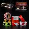 Rollos de cinta de advertencia de PVC reflectante en rojo, blanco y amarillo, mostrados junto a un sistema de luces de seguri