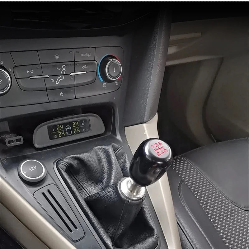 Close-up view of a black universal aluminum gear shift knob installed in a vehicle's interior