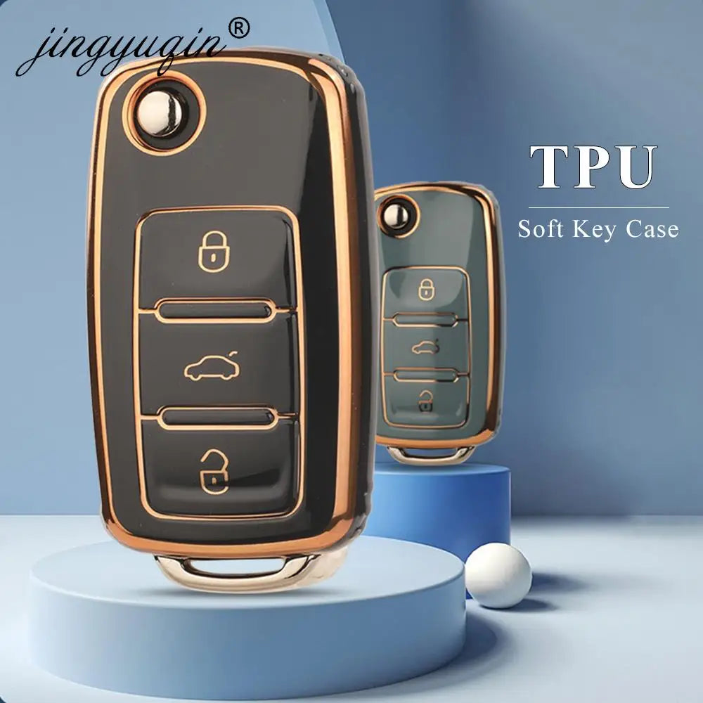 A close-up view of a black and gold TPU soft key case for a car key, displayed on a light blue surface.