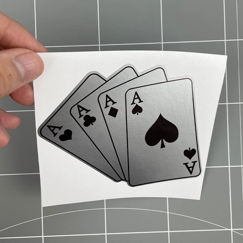 A hand holds a stack of black and gray poker themed motorcycle decals on a white card.