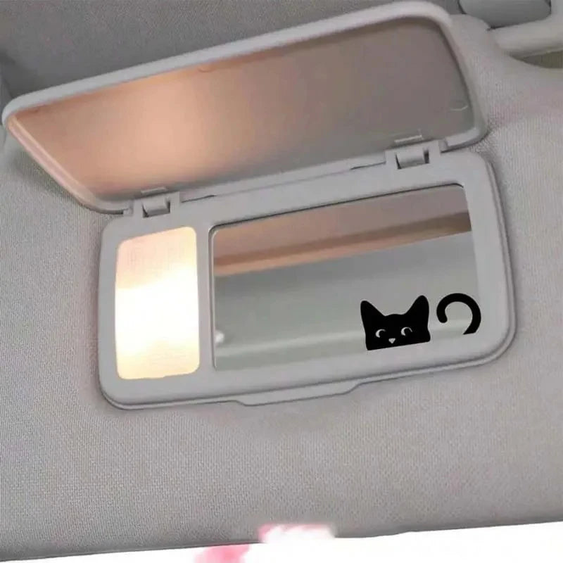 A clear plastic decal featuring a black cat face and a swirl design for use on a rearview mirror.