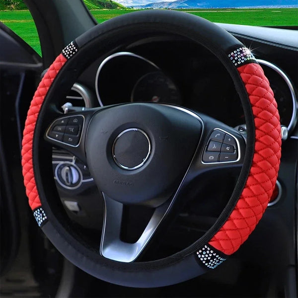 Close-up view of a black steering wheel with an orange embroidered leather cover and silver accents.