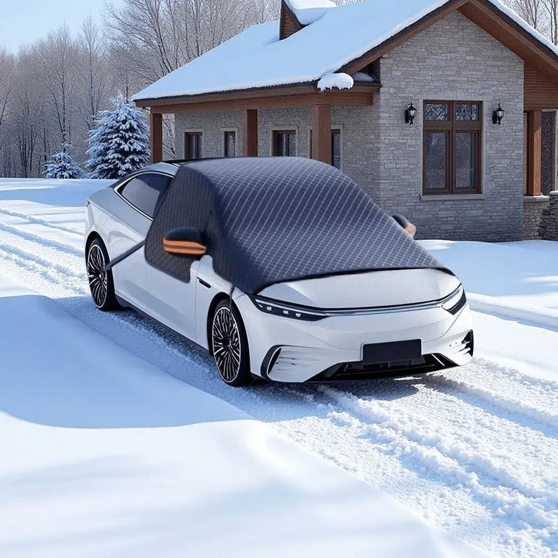 A white car with a black magnetic anti-frost windshield sunshade parked in the snow in front of a house.
