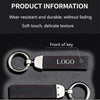 A close-up view of a black suede leather car keychain with a silver logo and stitching.