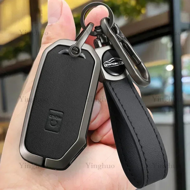 A black durable zinc alloy key fob cover attached to a leather strap, held in a hand.