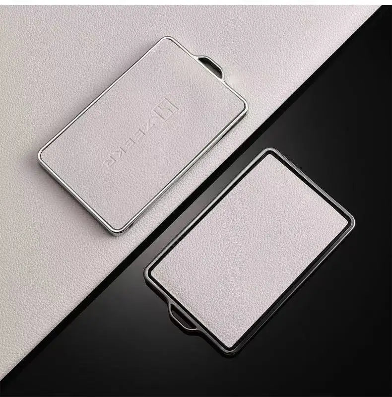Housse de clé NFC argentée pour clés automobiles posée sur une surface noire.
