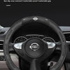 A black carbon fiber pattern steering wheel cover installed on a Nissan vehicle's steering wheel.