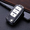 Black TPU leather car key case with multiple buttons resting on a dark brown leather surface.