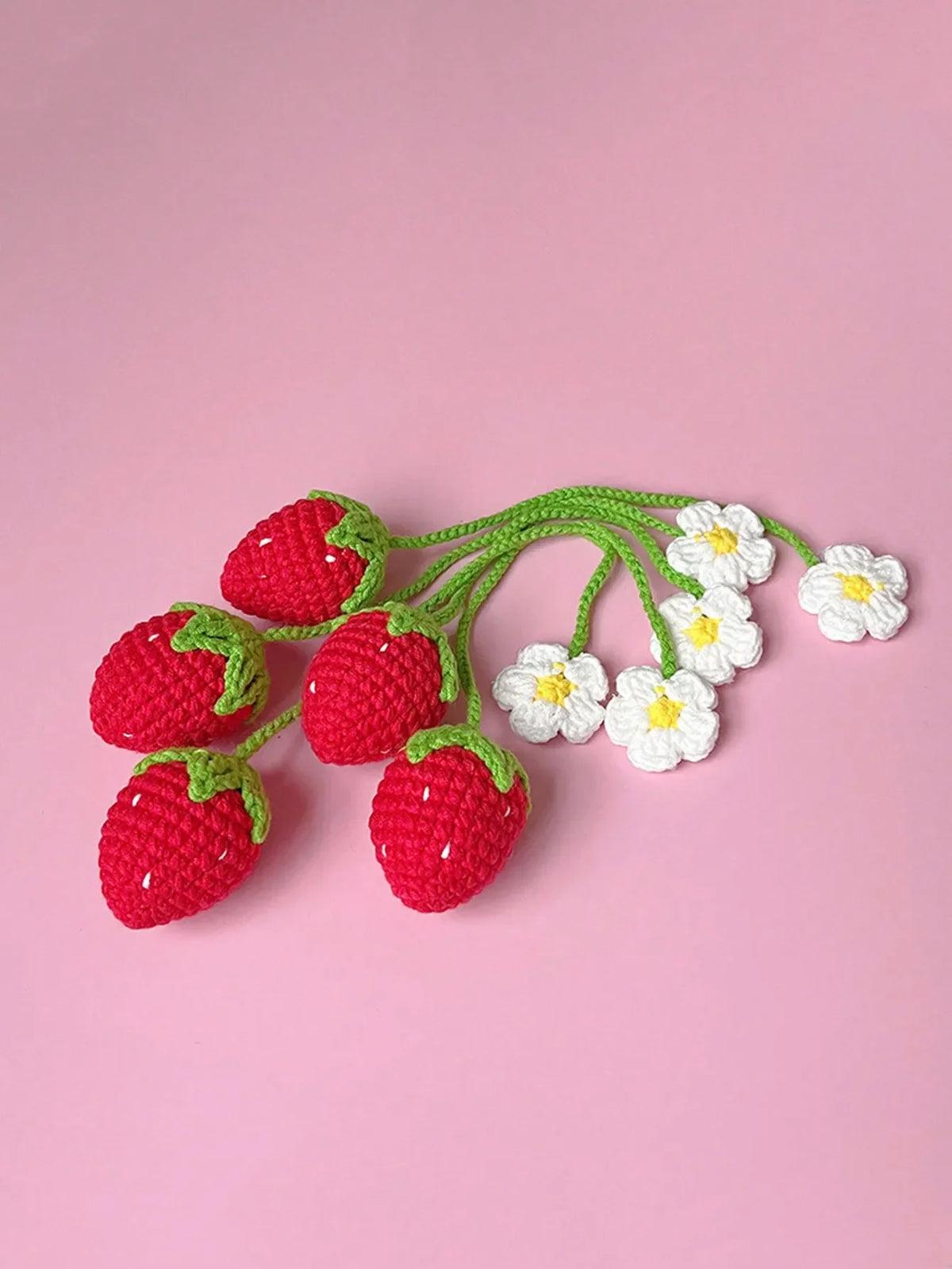 Fruit de fraise crochet fait main avec des accents de fleurs blanches sur une tige verte