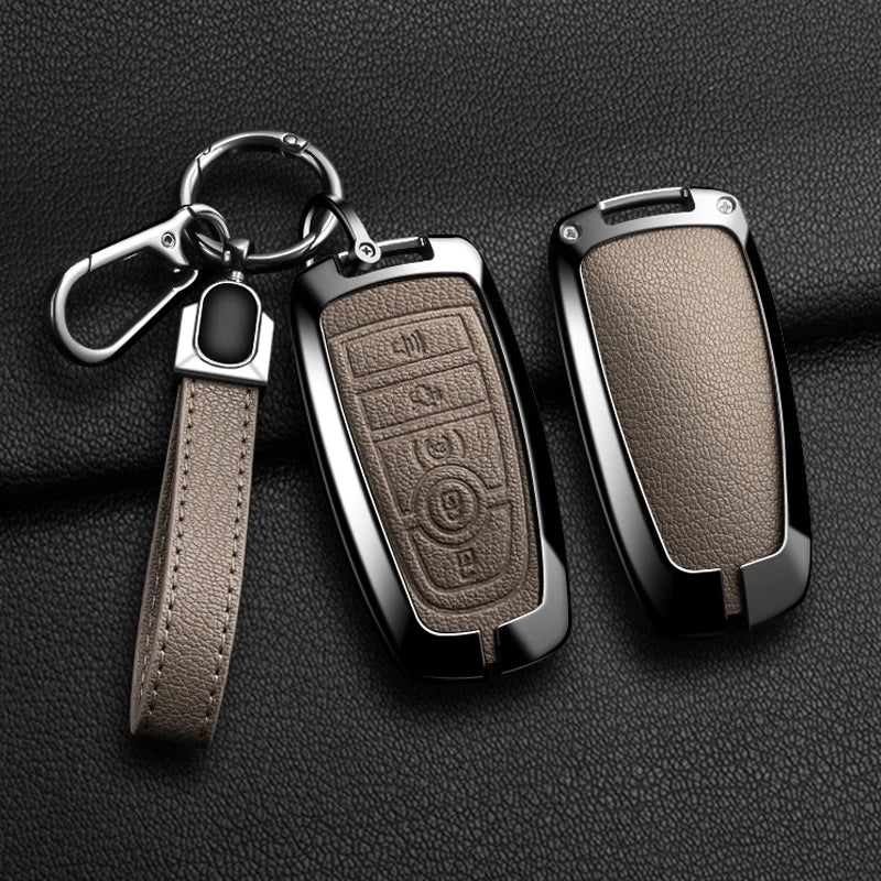 A black aluminum alloy key fob cover with a leather strap and keyring displayed on a dark surface.