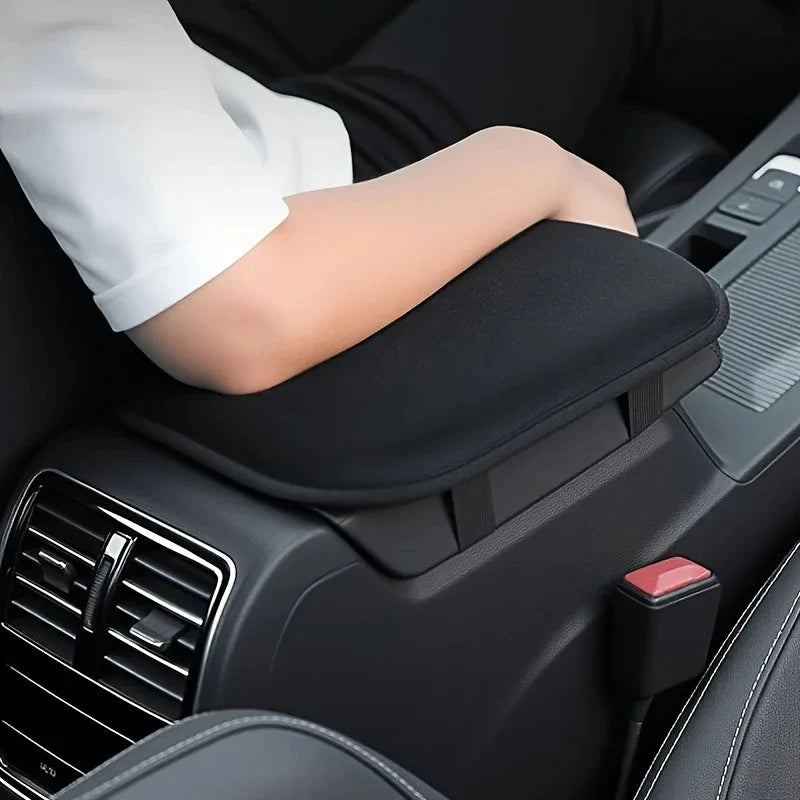 Eine Hand ruht auf der Armlehnenpolster-Stütze eines schwarzen Autos im Innenraum.
