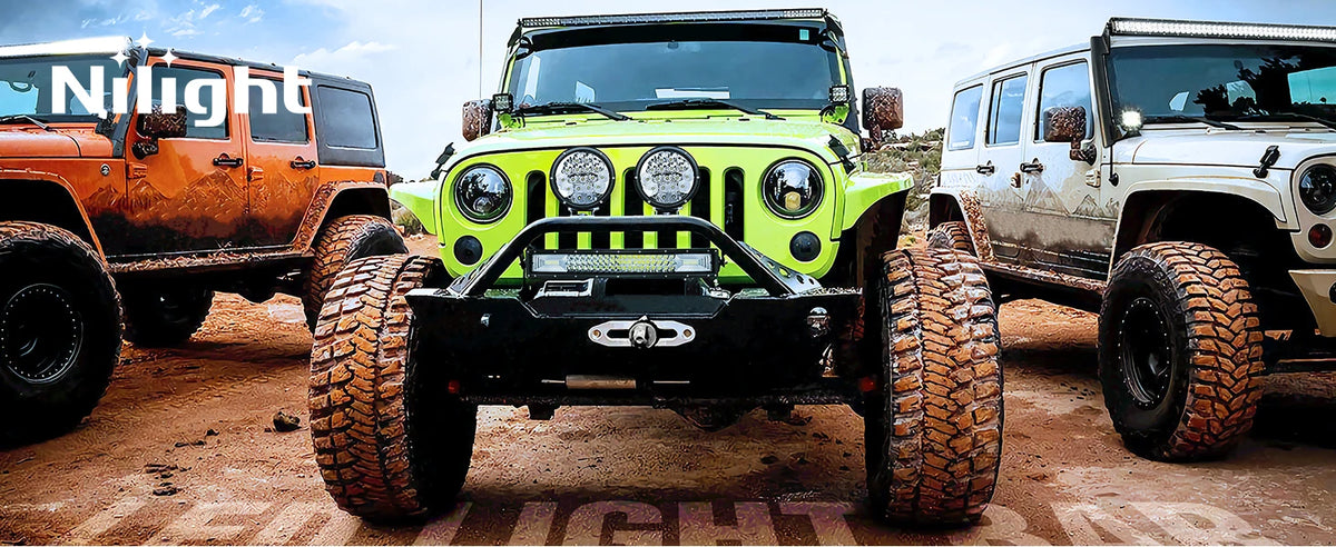 Three off-road vehicles, including a lime green Jeep, are parked on dirt terrain.