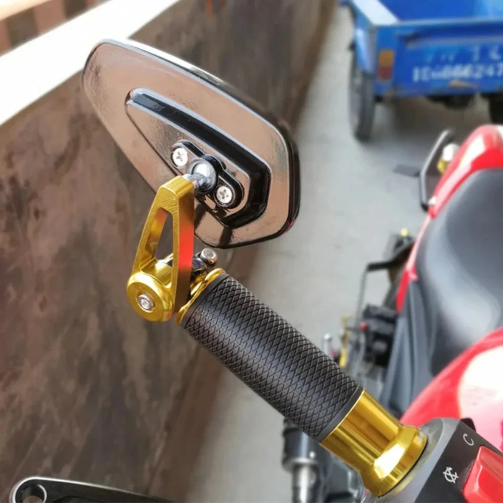 Close-up of a gold-colored motorcycle rearview mirror with a black textured grip and chrome mounting plate.