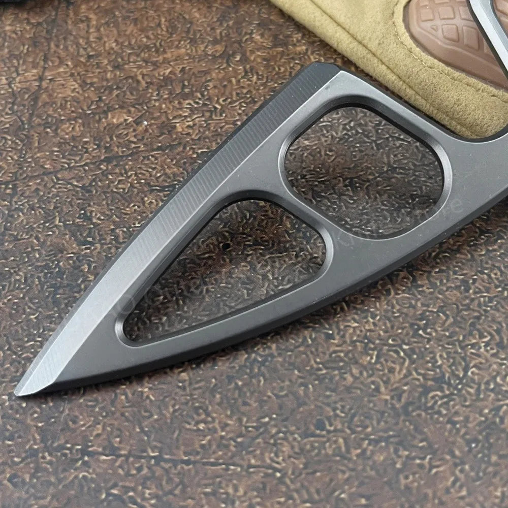 A close-up of a gray fixed blade survival knife with a serrated blade and a textured handle resting on a dark surface.