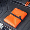 Orange waterproof car trunk liner mat placed on a black car surface.
