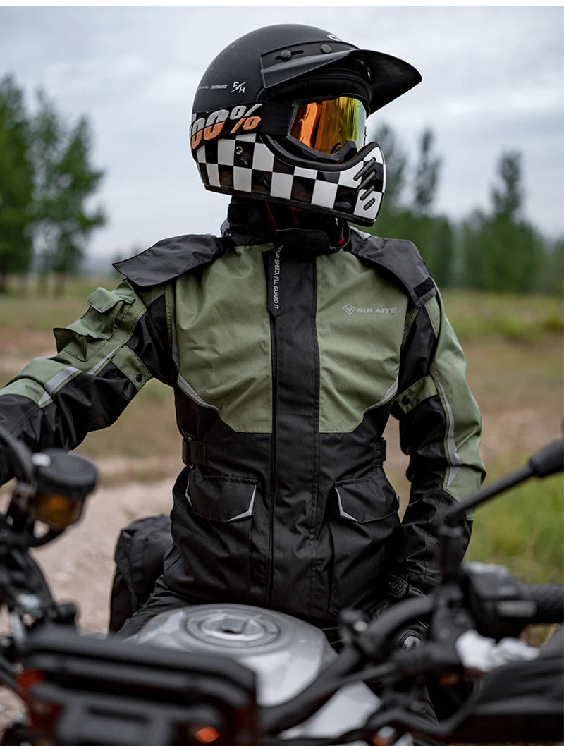 A person wearing a black and white checkered helmet and a green waterproof motorcycle raincoat sits on a motorcycle.