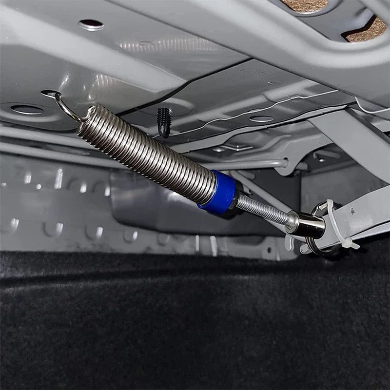 Un outil de levage argenté engage un loquet à l'intérieur du coffre d'une voiture.