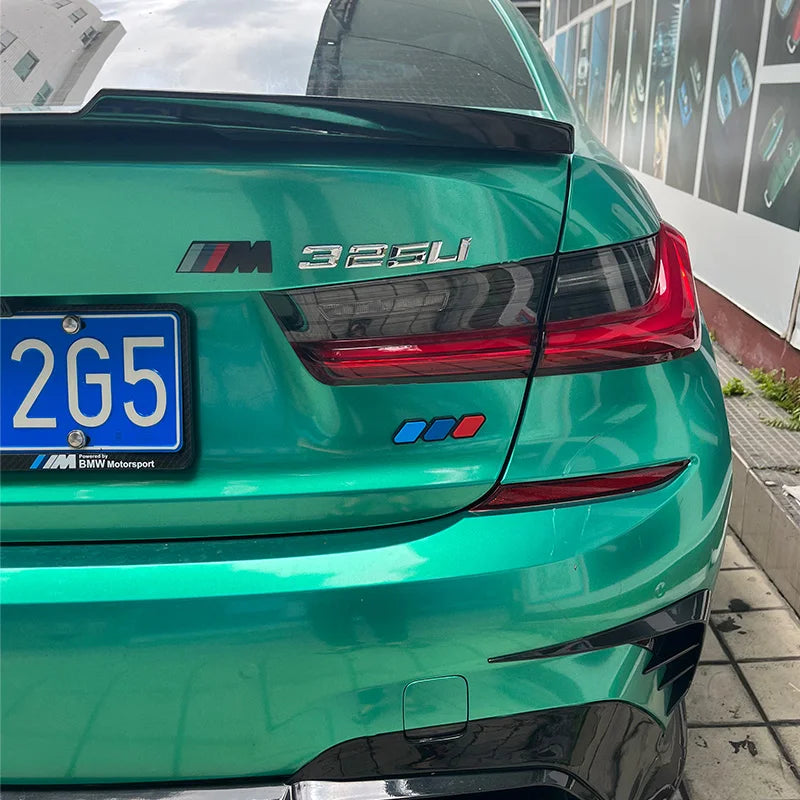 Rear view of a green BMW with an M325i badge and license plate parked outdoors.