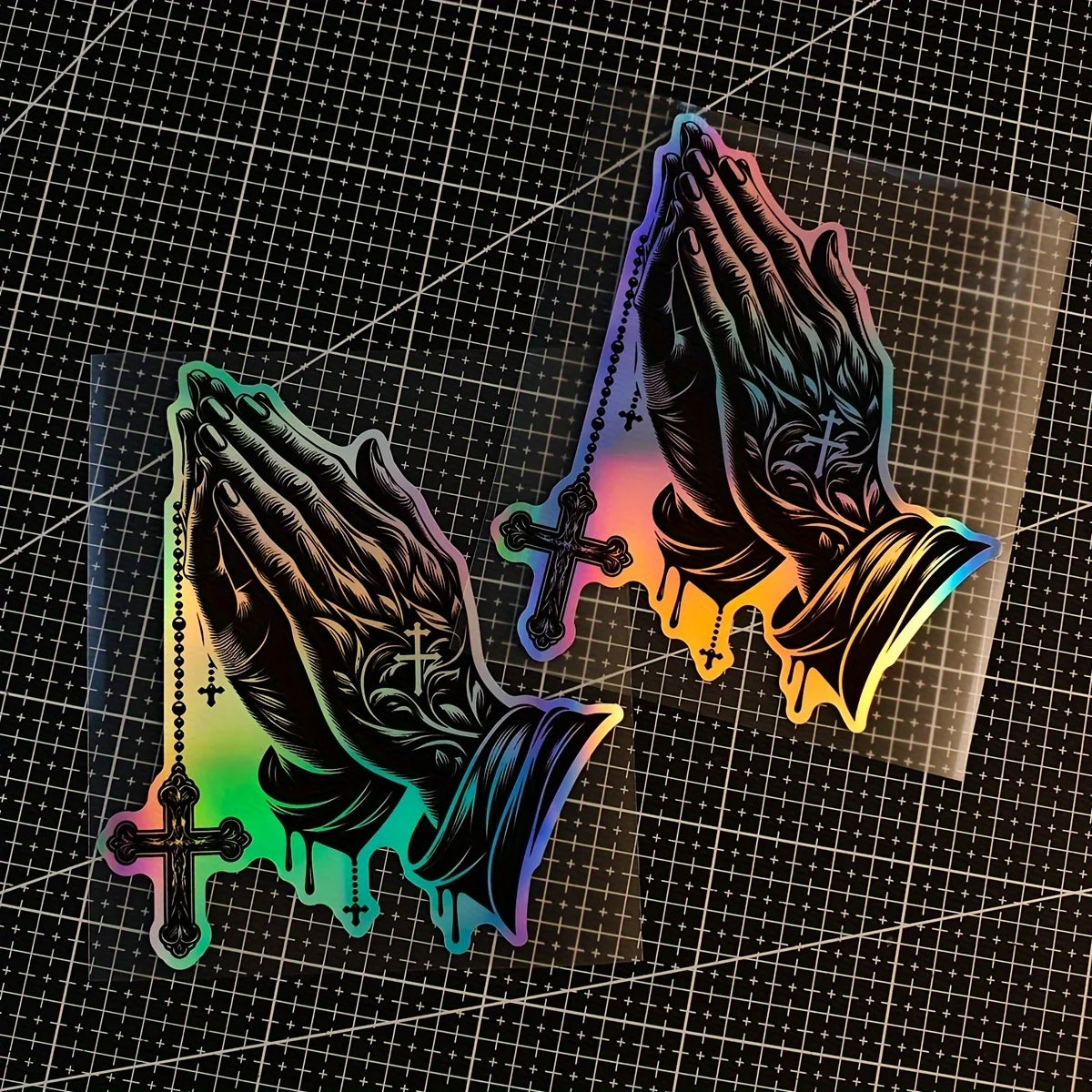 A decal featuring praying hands with a cross design, displayed against a dark grid background.