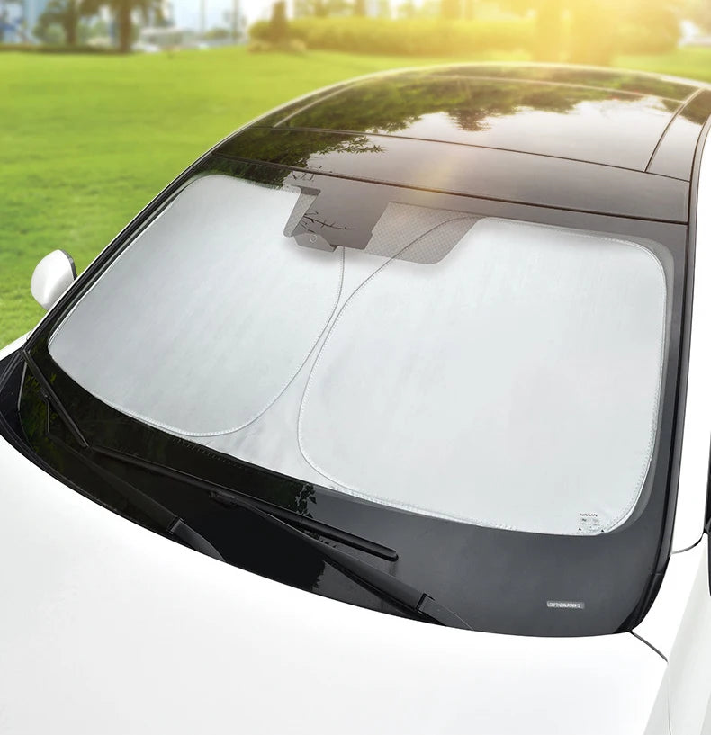 Un pare-soleil de voiture haut de gamme est installé sur une voiture blanche, visible de l'avant.