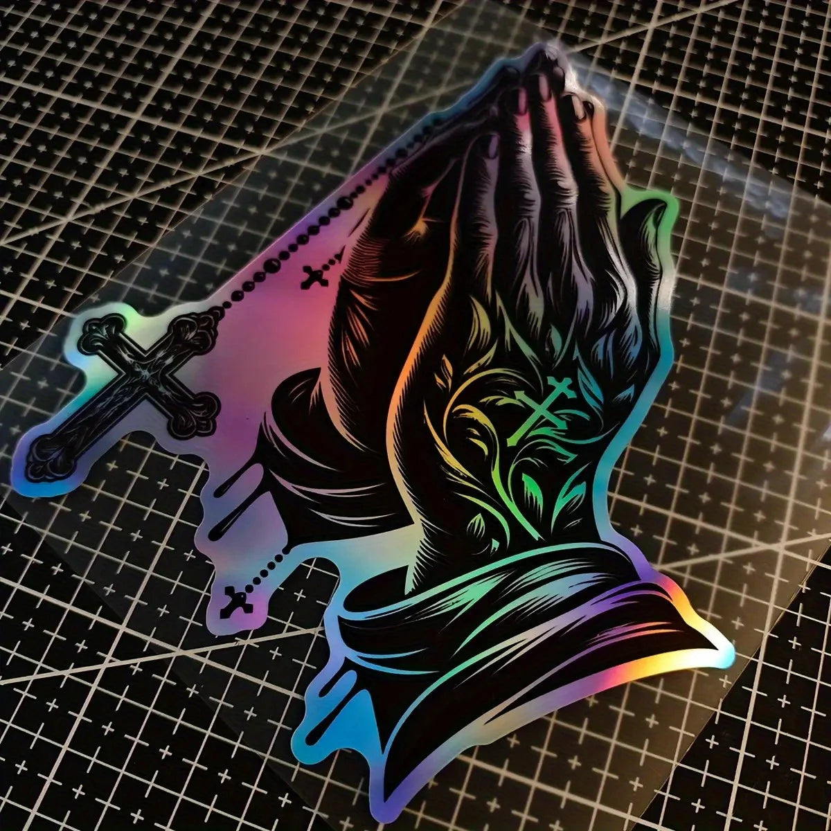 A decal featuring praying hands with a cross design, displayed on a grid background.