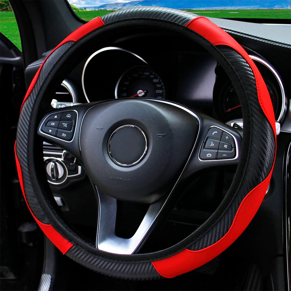 A black steering wheel with a red accent rim and carbon fiber grip on a car interior.