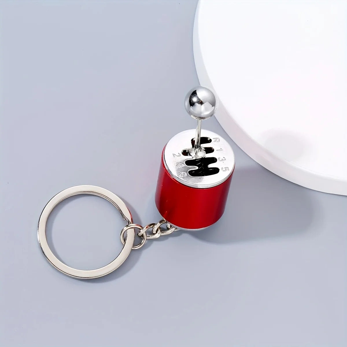 A red and silver keychain with a spherical top and a ring, designed for desk stress relief.