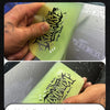 A hand is applying a sheet of clear film onto a surface, demonstrating the invisible car film scraper tool.