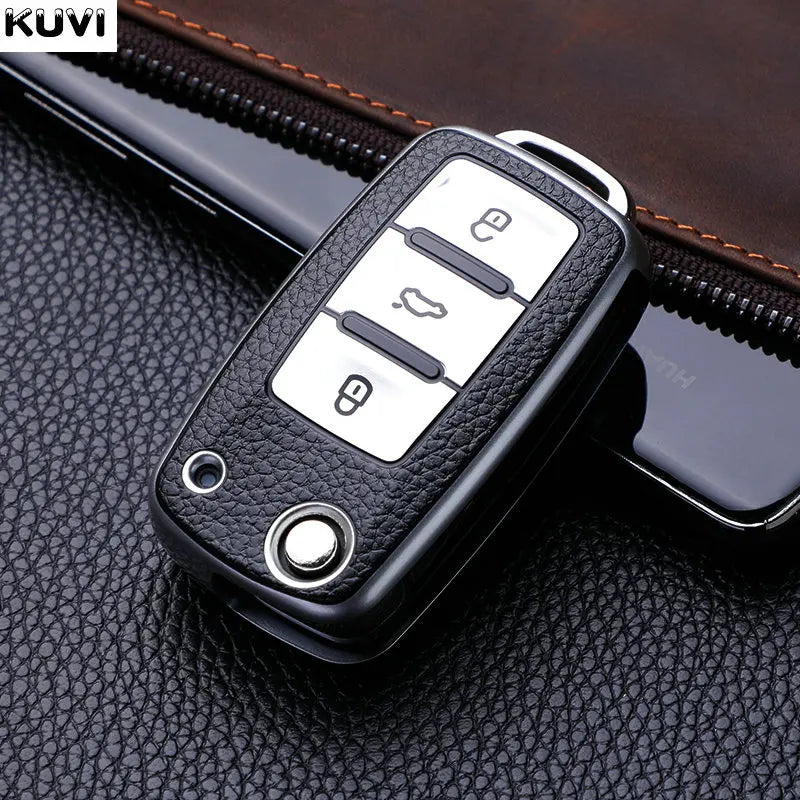 Black TPU car key cover with multiple buttons resting on a dark brown leather surface.