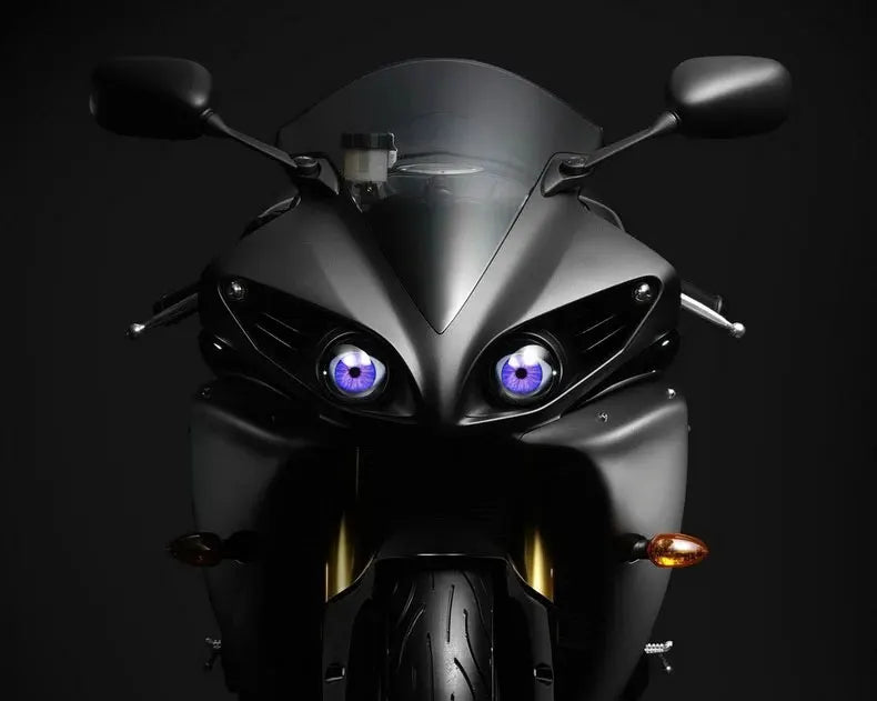 Close-up of a black vehicle headlight featuring bright blue LED eye lights.