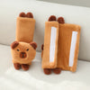 A pair of plush capybara car neck pillows in brown and white fabric resting on a light surface.