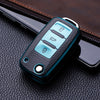 A teal TPU leather car key case with multiple buttons rests on a dark brown leather surface.