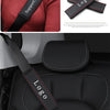 Black leather logo shoulder strap pad for car seat belts shown on a red sweater and a black car seat.